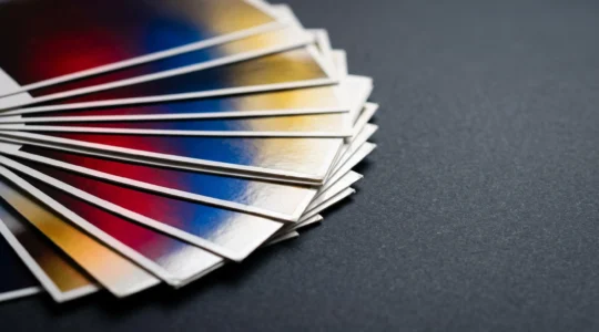 Cartes imprimées en couché brillant révélant des couleurs saturées sous une lumière directionnelle